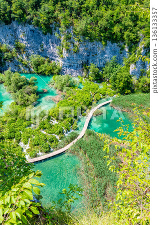Aerial view of wooden footpath trail at Plitvice lakes, Croatia. Tourist path above blue lagoon near the waterfalls. Empty bridge without peoples. Aerial view of wooden footpath trail at Plitvice lakes, Croatia. Tourist path above blue lagoon near the waterfalls. Empty bridge without peoples. 136133357