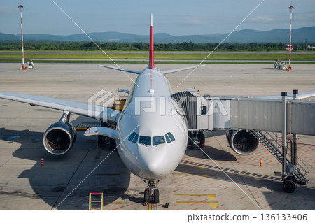 Passenger jet preparing for departure at airport, connected to boarding bridge 136133406