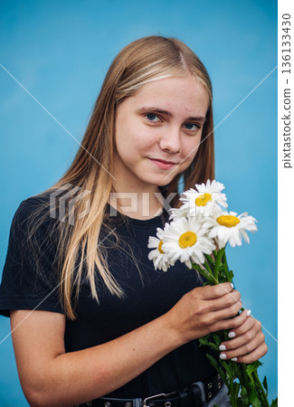 Young blonde girl holding daisies, expressing spring freshness and innocent beauty Young blonde girl holding daisies, expressing spring freshness and innocent beauty 136133430