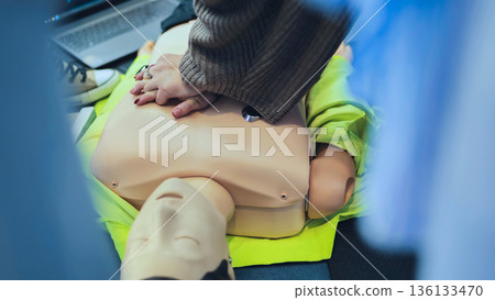 Hands performing cardiopulmonary resuscitation on a training mannequin for first aid 136133470