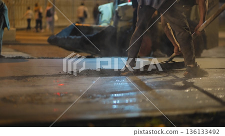 Road maintenance crew laying fresh asphalt at night, improving urban infrastructure Road maintenance crew laying fresh asphalt at night, improving urban infrastructure 136133492