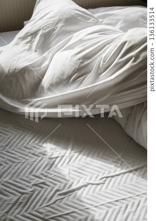 Closeup of wrinkled white pillow and blanket in soft light 136133514