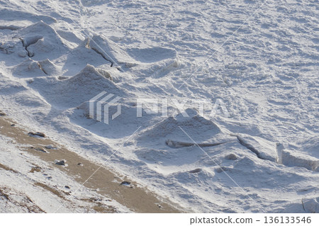Frozen wave formations line the shoreline of Lake Baikal, creating sculpted ice ridges and textured snow under cold daylight 136133546
