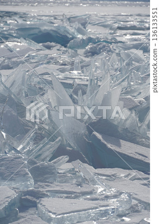 Sharp translucent ice plates, turquoise shards form dramatic frozen patterns on the surface of Lake Baikal with distant mountains in soft winter light Sharp translucent ice plates, turquoise shards form dramatic frozen patterns on the surface of Lake Baikal with distant mountains in soft winter light 136133551