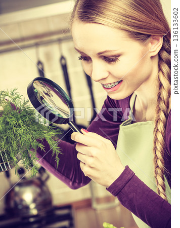 Woman looking magnifier at vegetables 136133602
