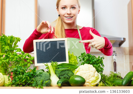 Woman having green vegetables holding board 136133603