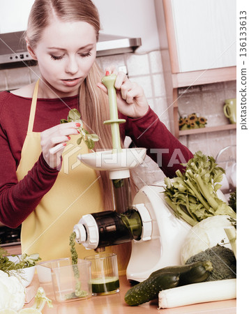 Woman in kitchen making vegetable smoothie juice Woman in kitchen making vegetable smoothie juice 136133613