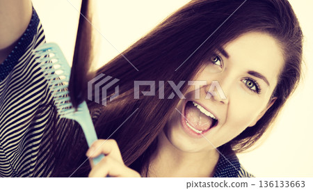 Woman brushing her long hair using comb Woman brushing her long hair using comb 136133663