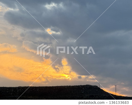 Dramatic sunset sky over rocky landscape. Sunset over rolling hills. Dramatic sunset sky over rocky landscape. Sunset over rolling hills. 136133683