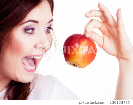 Woman holds apple fruit close to face, isolated Woman holds apple fruit close to face, isolated 136133795