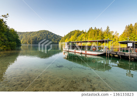 Tourist boat on Plitvice lakes shortly after sunrise. Soft light, vibrant colors. Croatia national nature park. Tourist boat on Plitvice lakes shortly after sunrise. Soft light, vibrant colors. Croatia national nature park. 136133823