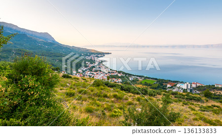 Aerial view of Tucepi town, Croatia. Makarska - Dalmatia region. View of city, sea and isle ind the background. Sunrise time. Aerial view of Tucepi town, Croatia. Makarska - Dalmatia region. View of city, sea and isle ind the background. Sunrise time. 136133833
