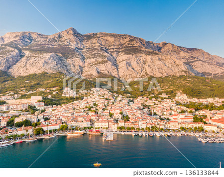 Drone aerial view of Makarska city, Croatia. Sunset over the city, beach and se. Biokovo mountains in the background. Summer time. 136133844