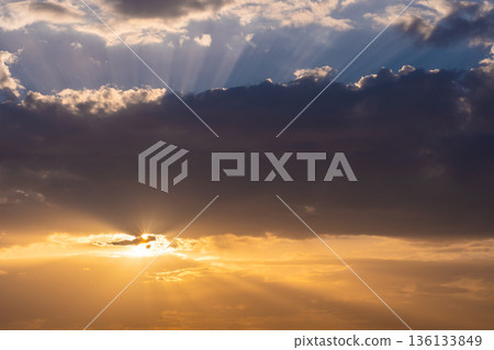 The sunset over the clouds. Warm colors, light flares from the sun. 136133849