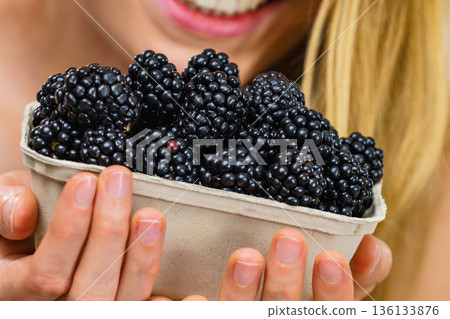 Girl holds blackberry fruits 136133876