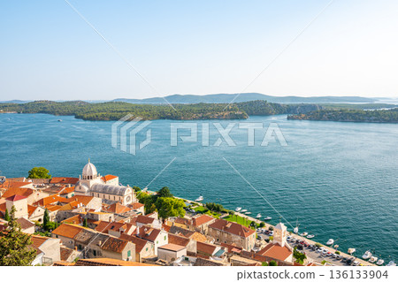 Coastal view of Sibenik old city, Croatia. Cathedral of St James, adriatic sea with island in background. Summer weather, aerial view of city roofs. UNESCO heritage. Coastal view of Sibenik old city, Croatia. Cathedral of St James, adriatic sea with island in background. Summer weather, aerial view of city roofs. UNESCO heritage. 136133904