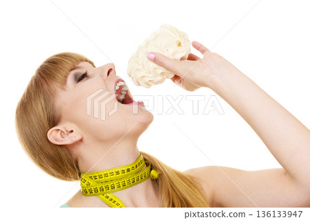 Woman holds cupcake trying to resist temptation 136133947
