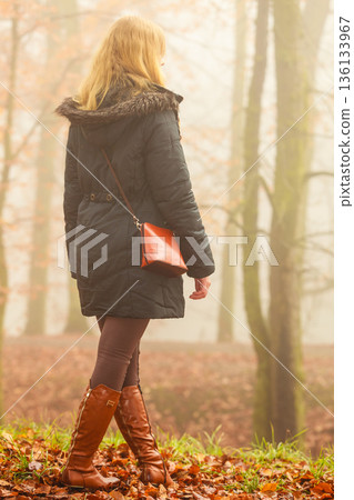Woman walking in park in foggy day Woman walking in park in foggy day 136133967
