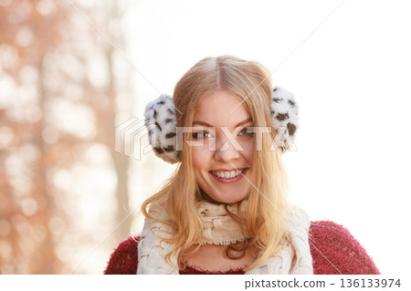 Portrait of pretty smiling woman in fur earmuffs. 136133974