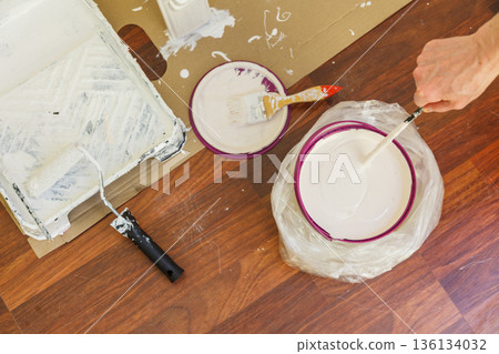 Person mixing white paint in bucket. Person mixing white paint in bucket. 136134032