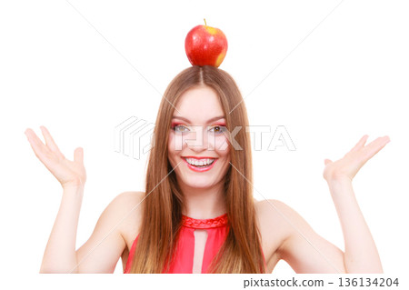 Beautiful woman holds apple fruit on head Beautiful woman holds apple fruit on head 136134204