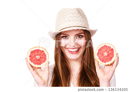 Woman holds two halfs of grapefruit citrus fruit in hands Woman holds two halfs of grapefruit citrus fruit in hands 136134205