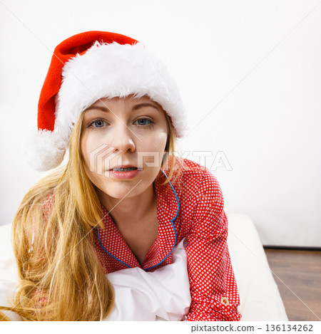 Happy woman wearing pajamas and Santa Claus hat 136134262