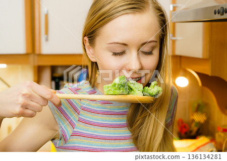 Woman tasting stir fry vegetable from pan 136134281