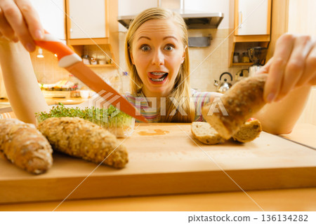 Woman in kitchen holding knife making healthy sandwich Woman in kitchen holding knife making healthy sandwich 136134282