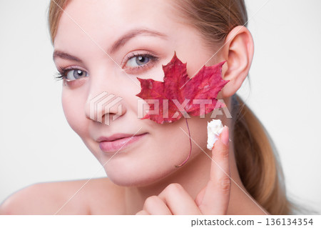 Skin care. Face of young woman girl with red maple leaf. Skin care. Face of young woman girl with red maple leaf. 136134354