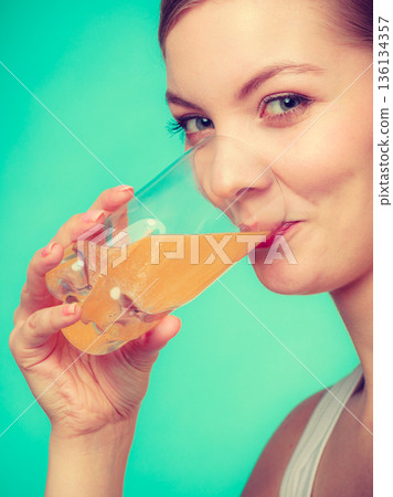 Woman drinking orange flavored drink or juice 136134357