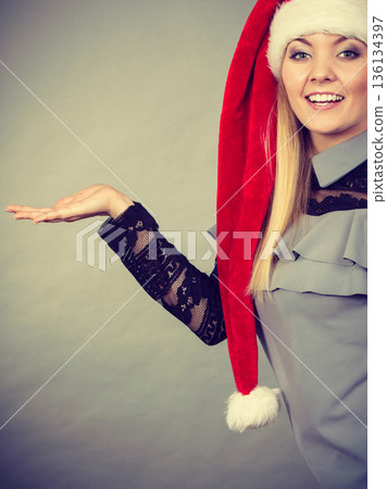 Happy woman wearing Santa Claus helper hat 136134397