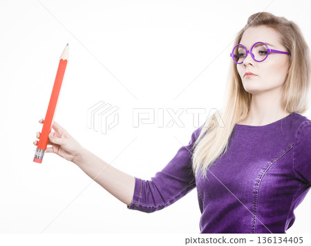 Serious woman holds big pencil in hand 136134405