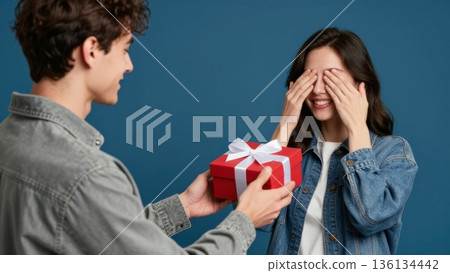 Couple Exchanging Presents, Intimate Indoor Setting With Couple Sharing Heartfelt Gift Exchange Moment, Warm Evening Event Where Young Man Privately Presents Meaningful Gift To His Partner 136134442