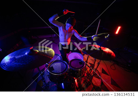 Energetic drummer performing live music on dark stage 136134531