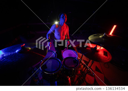 Musician playing drums on stage during a vibrant music show Musician playing drums on stage during a vibrant music show 136134534