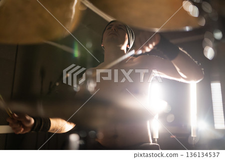 Energetic drummer playing music with drumsticks Energetic drummer playing music with drumsticks 136134537