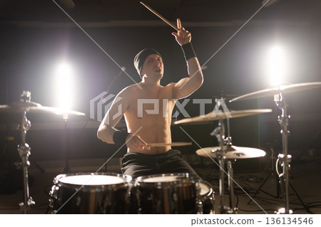 Male drummer playing drums with energy on stage Male drummer playing drums with energy on stage 136134546