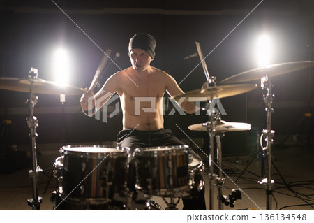 Drummer playing drums with intensity on stage Drummer playing drums with intensity on stage 136134548
