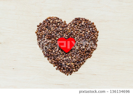 buckwheat groats heart shaped on wooden surface. 136134696