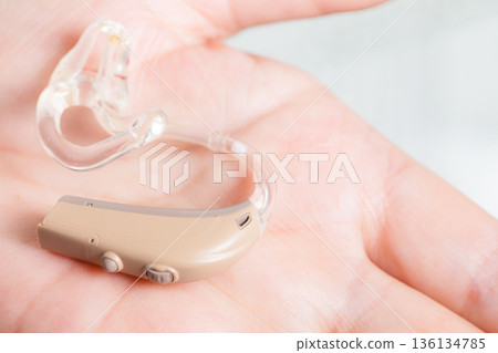 senior person holding hearing aid closeup 136134785