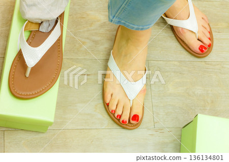 Unrecognizable woman trying on flip flops Unrecognizable woman trying on flip flops 136134801