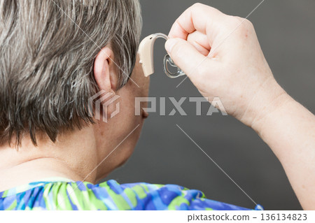 Closeup senior woman using hearing aid 136134823