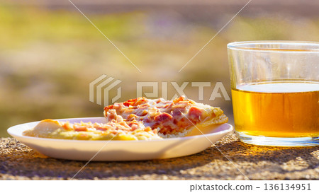 Tea mug and pizza slices on plate, outdoors 136134951
