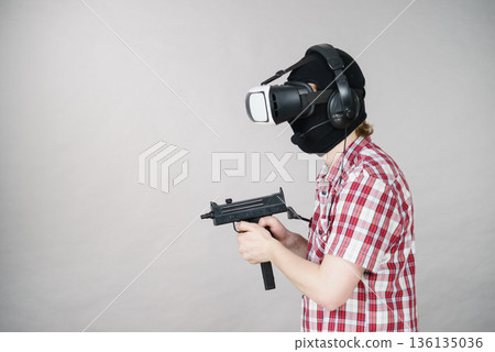 Gamer man wearing VR holding gun Gamer man wearing VR holding gun 136135036