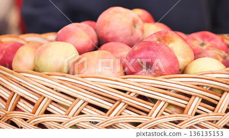 Freshly picked red and yellow apples filling a rustic wicker basket during harvest season 136135153