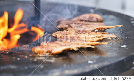 Fish grilling over fire on street food barbecue Fish grilling over fire on street food barbecue 136135229
