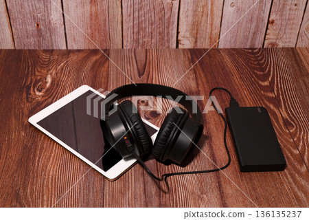 black headphones lying on a tablet and power bank 136135237