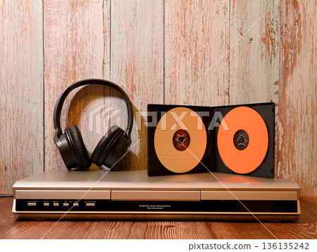 headphones and a case with discs on a silver player headphones and a case with discs on a silver player 136135242