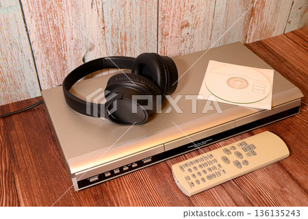 headphones and a disc in an envelope on a silver player headphones and a disc in an envelope on a silver player 136135243
